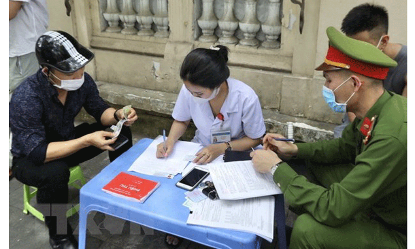 Lực lượng chức năng xử phạt hành chính với người không đeo khẩu trang nơi công cộng. (Ảnh: Minh Quyết/TTXVN)