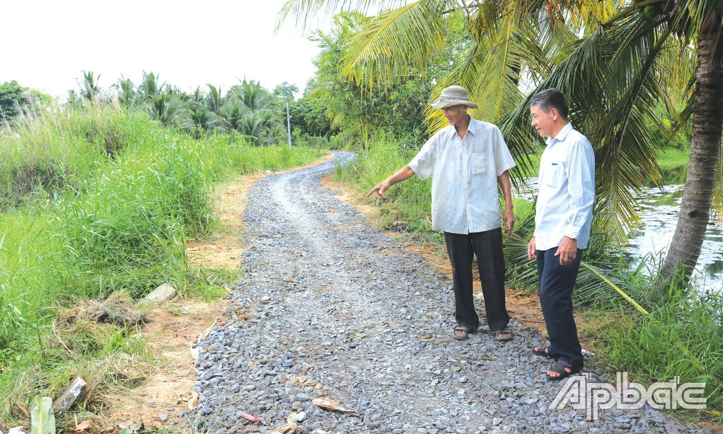 Ông Tươi (bên trái) trên tuyến đường số 2  (ấp 6, xã Phú An) do ông vận động kinh phí,  ngày công nâng cấp.