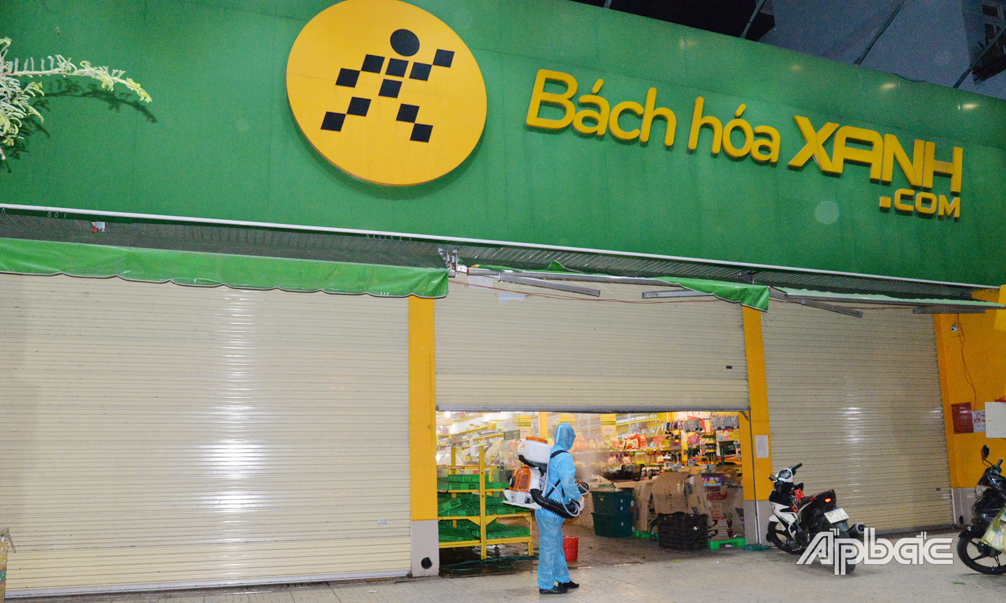 Nhân viên y tế phun khử khuẩn cửa hàng Bách hóa xanh tại phường 3 vào tối 15-6