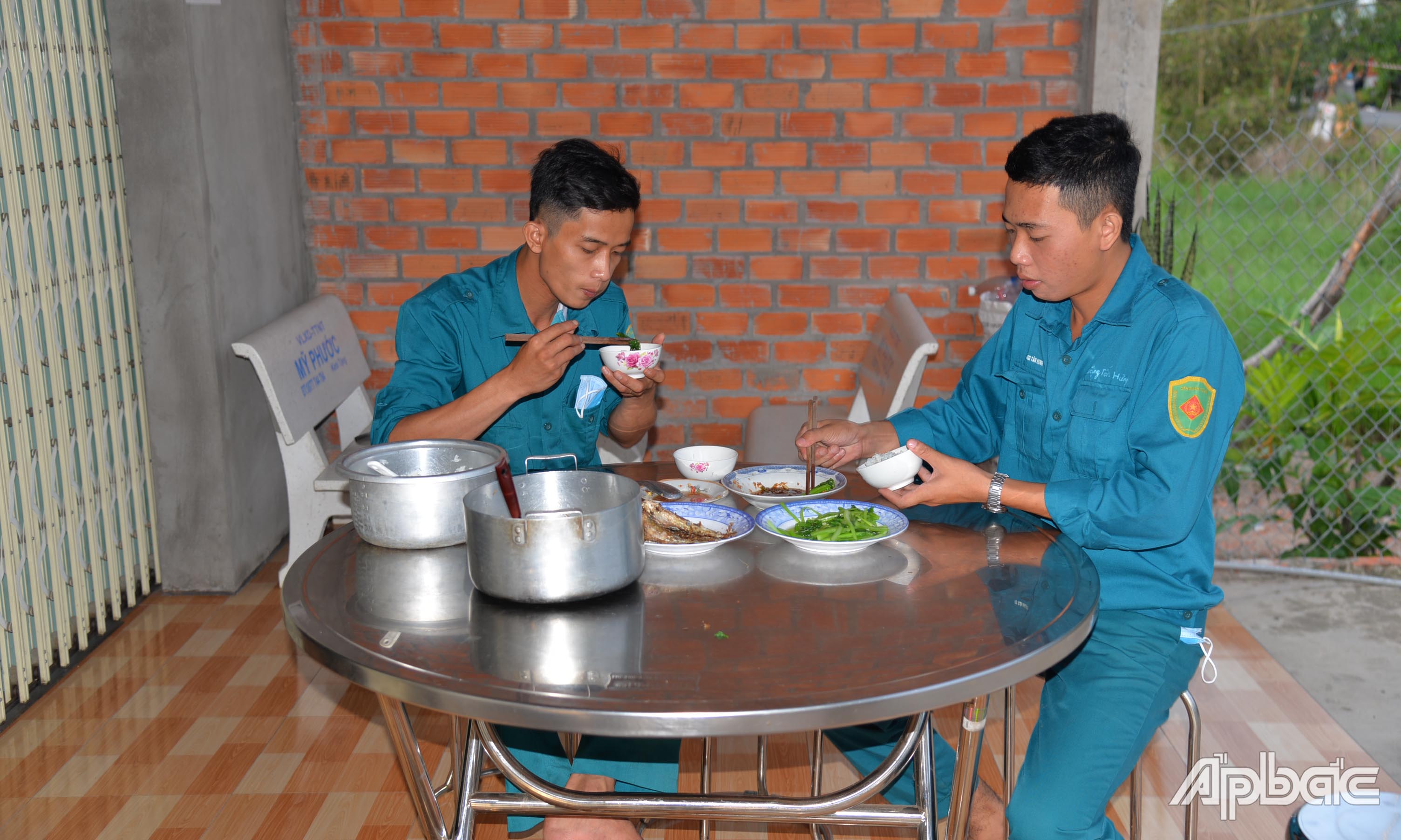 Lực lượng làm nhiệm vụ tại chốt phong tỏa trên đường huyện 59 dùng vội bữa cơm chiều do một người dân gần đó nấu hỗ trợ.