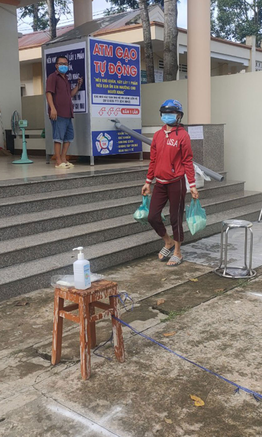 Người dân nhận gạo miễn phí tại máy “ATM” gạo đặt tại Trung tâm Văn hóa - Thể thao xã Long Hưng.