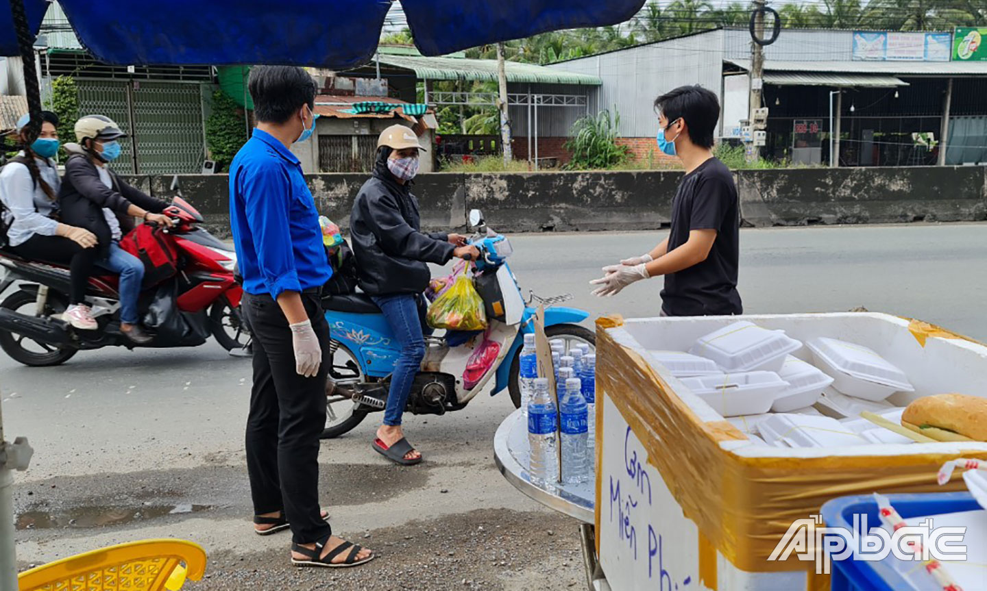 Các bạn đoàn viên cùng người dân phát phần ăn tại xã Nhị Bình, Châu Thành.