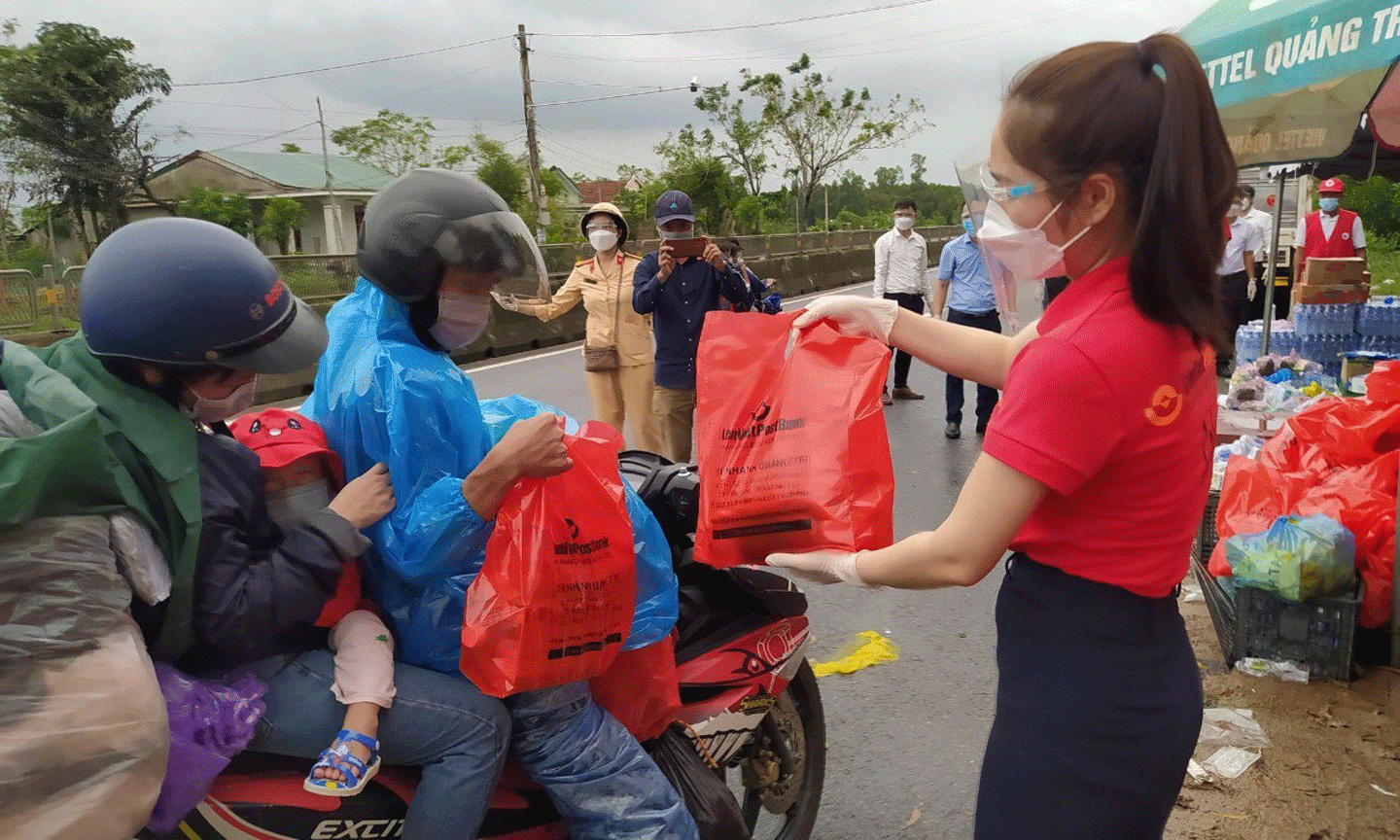 Trao tặng thức ăn và đồ dùng cho những người trở về bằng xe máy từ các tỉnh, thành phía Nam trên Quốc lộ 1A đoạn qua xã Hải Chánh, huyện Hải Lăng, tỉnh Quảng Trị. Ảnh: Thanh Thủy/TTXVN