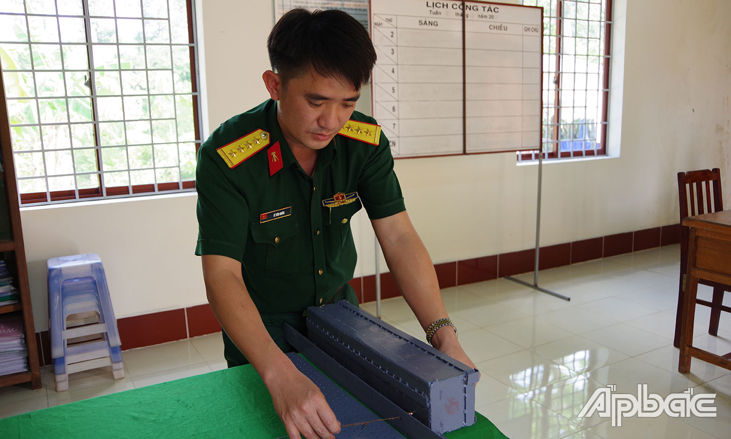 Đại úy Lê Văn Nhân bên sáng kiến “Thiết bị  thử tỷ lệ nổ cháy đồ dùng gây nổ và thử uy lực của kíp nổ”.