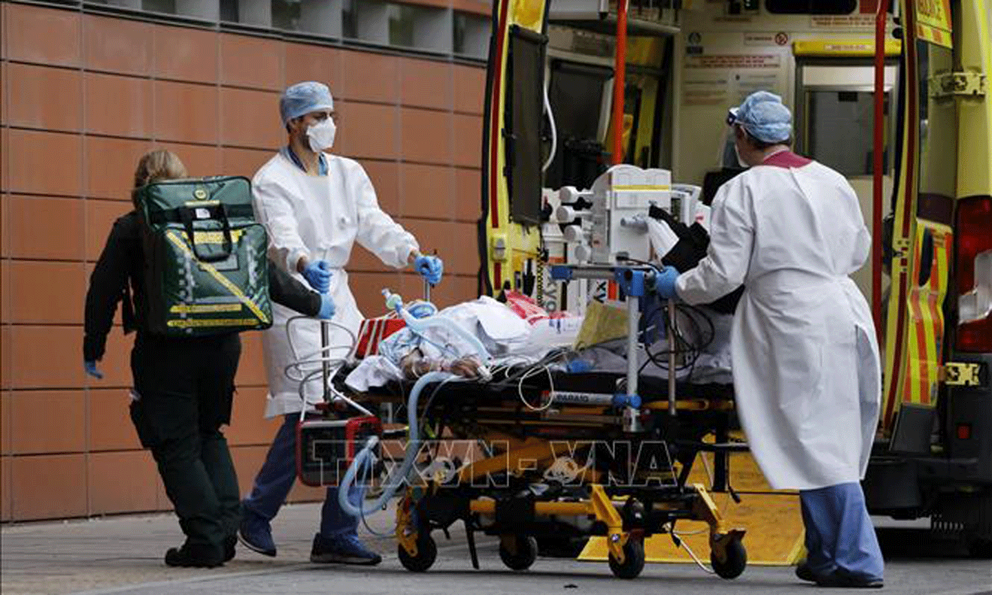 Nhân viên y tế chuyển bệnh nhân nhiễm COVID-19 tới bệnh viện ở London, Anh. Ảnh: AFP/TTXVN