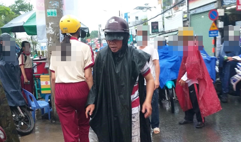 Người đàn ông (mặc áo đỏ sọc trắng, khoác áo mưa) tại hiện trường lúc xảy ra vụ án mạng đâm chết thanh niên dân quân tự vệ tại quận Gò Vấp, TP Hồ Chí Minh ngày 4-4 vừa qua. 