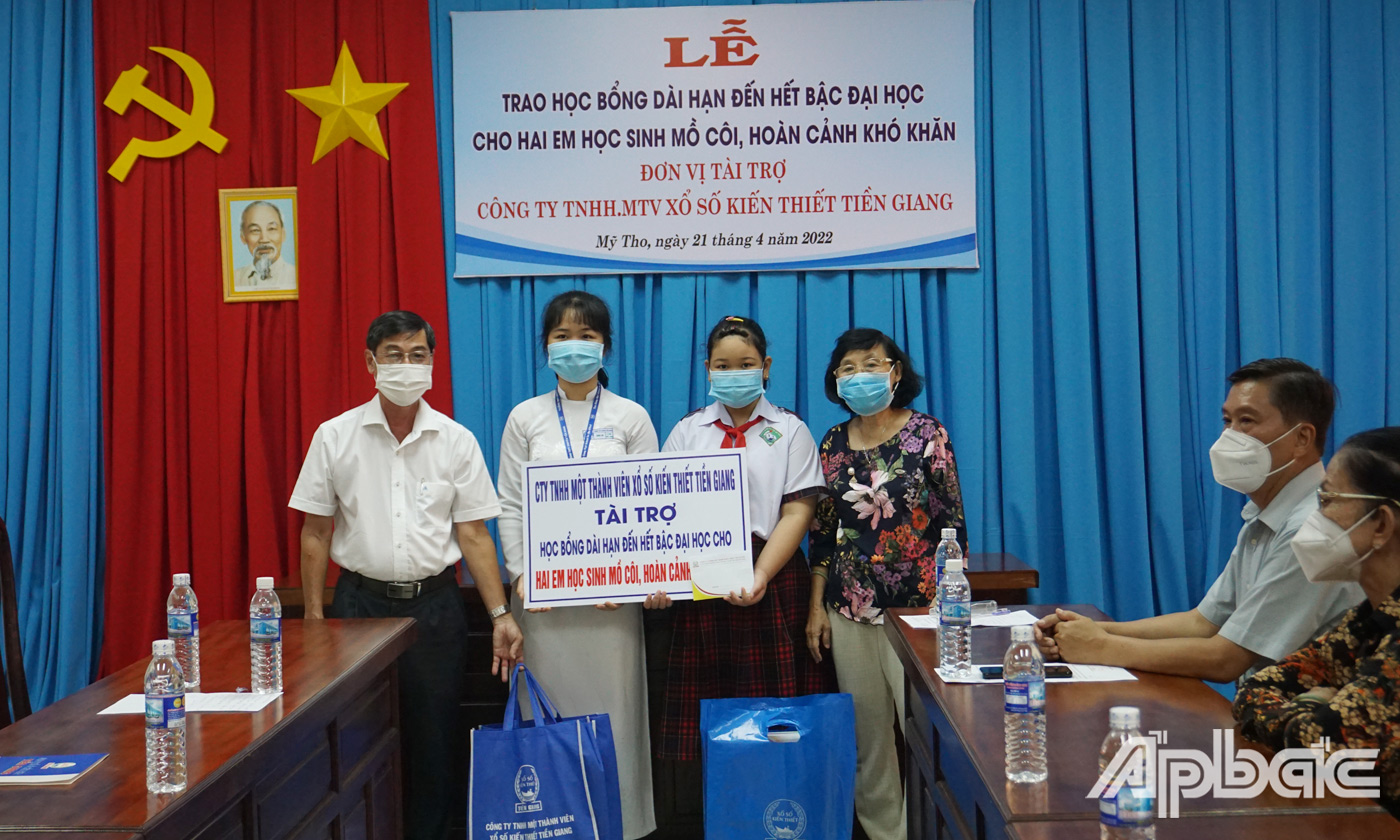 Đại diện Công Ty TNHH MTV Xổ số Kiến thiết Tiền Giang trao bảng tượng trưng cho hai em học sinh. 