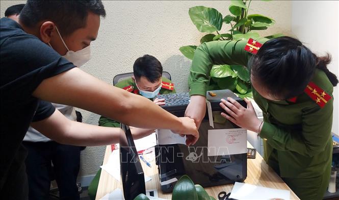 Lực lượng chức năng khám xét và niêm phong, thu giữ tài liệu tại trụ sở FLC. Ảnh: Phạm Kiên/TTXVN