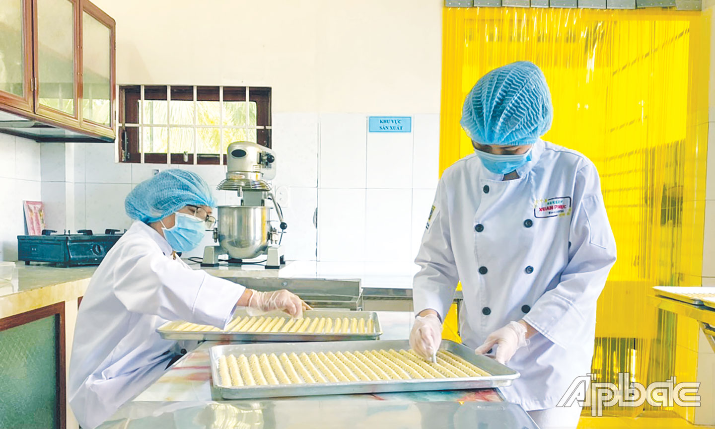 Chị Thy (đứng) đang tạo hình cho chiếc bánh quy dừa.