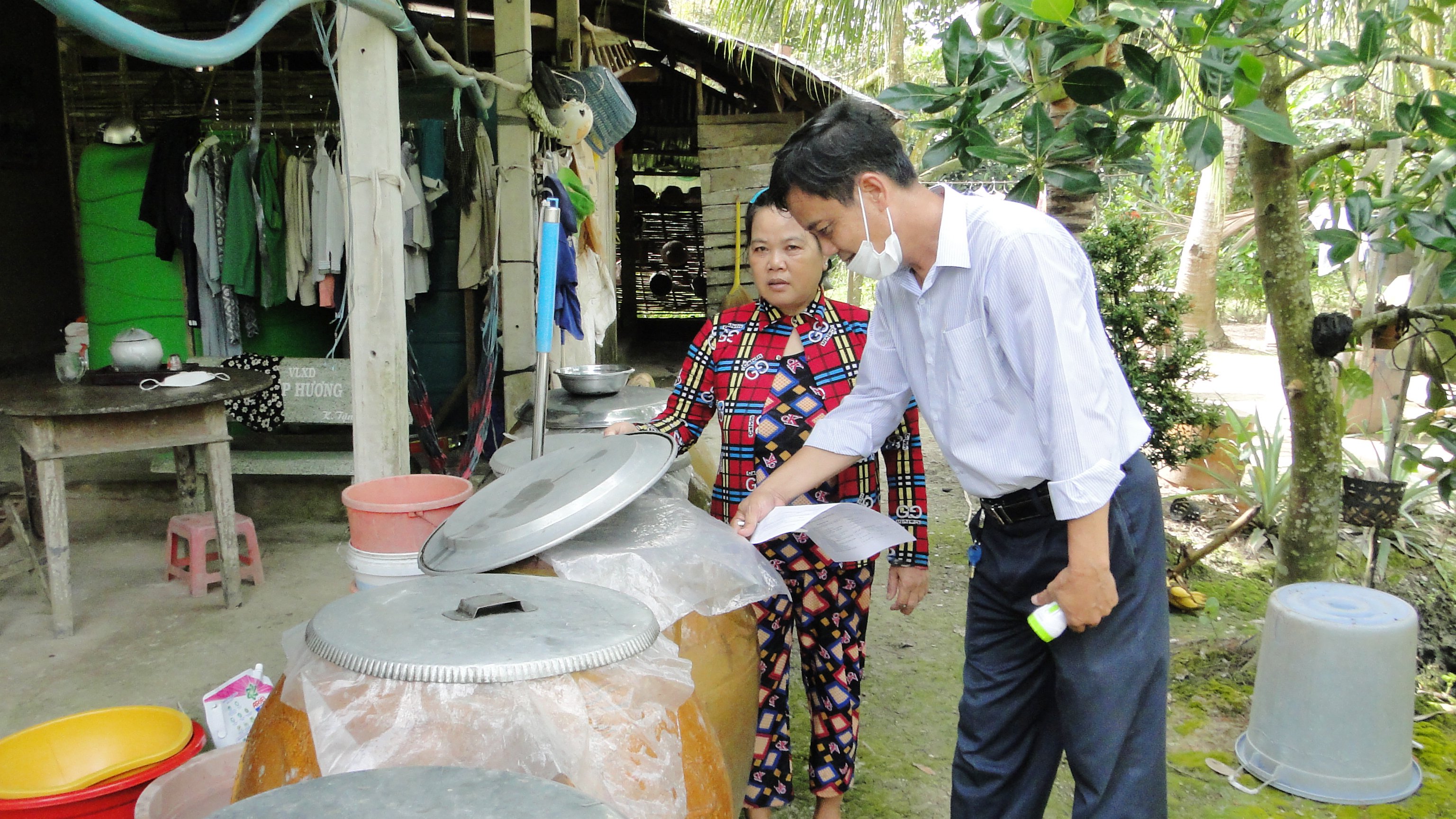 Cán bộ CDC kiểm tra SXH hộ gia đình và hướng dẫn đậy mũ các lu trữ nước đúng cách để không cho muỗi vào đẻ trứng tại Xã Hiệp Đức, huyện Cái Bè.