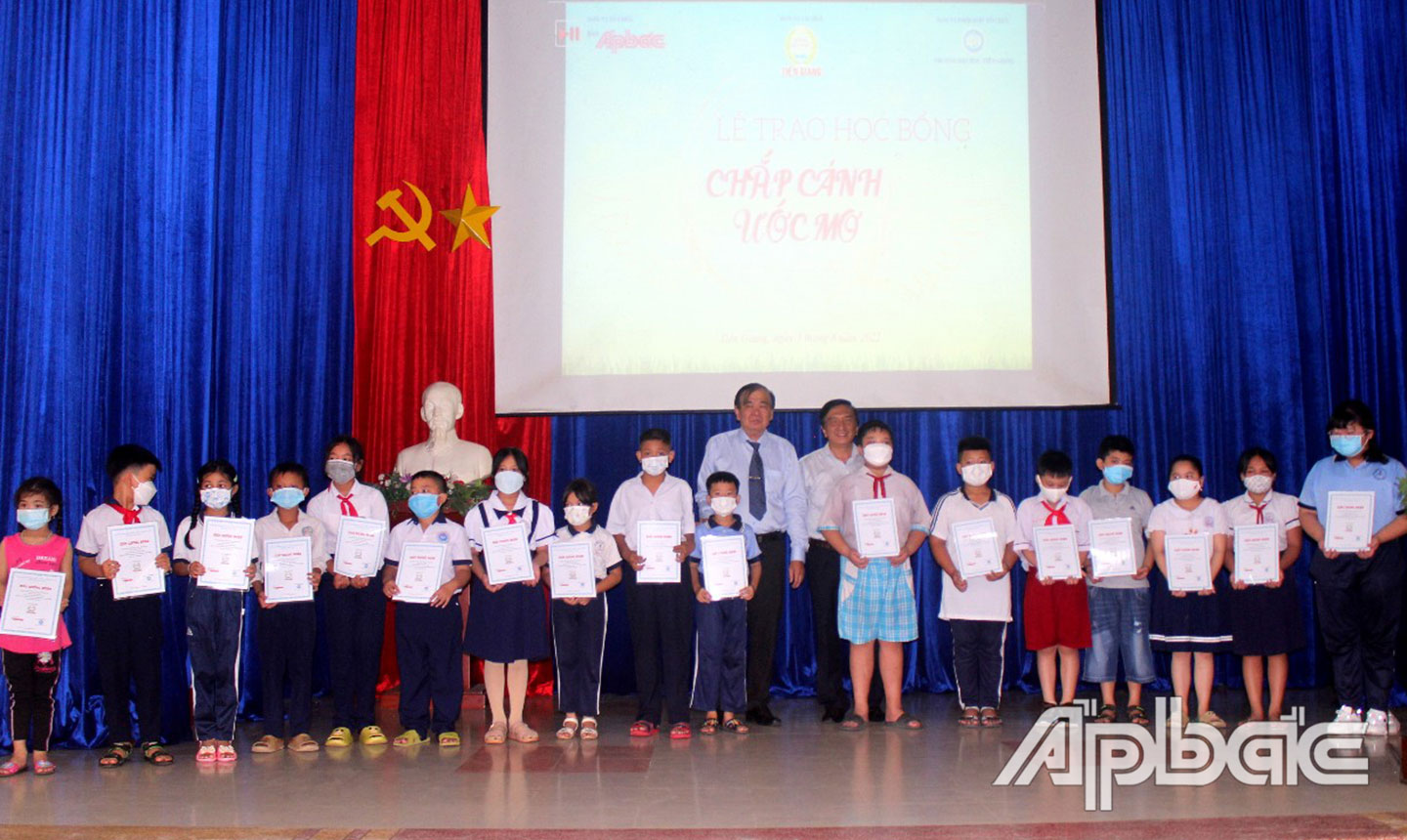 Tổng Biên tập Báo Ấp Bắc Nguyễn Minh Tân và Chủ tịch Hội đồng thành viên Công ty TNHH MTV Xổ số kiến thiết Tiền Giang Nguyễn Minh Hiếu trao học bổng cho các em học sinh.