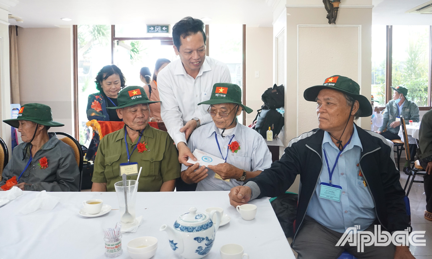 Phó Chủ tịch UBND tỉnh Nguyễn Thành Diệu cài hoa và tặng quà cho người có công trước khi tham quan thủ đô Hà Nội. 