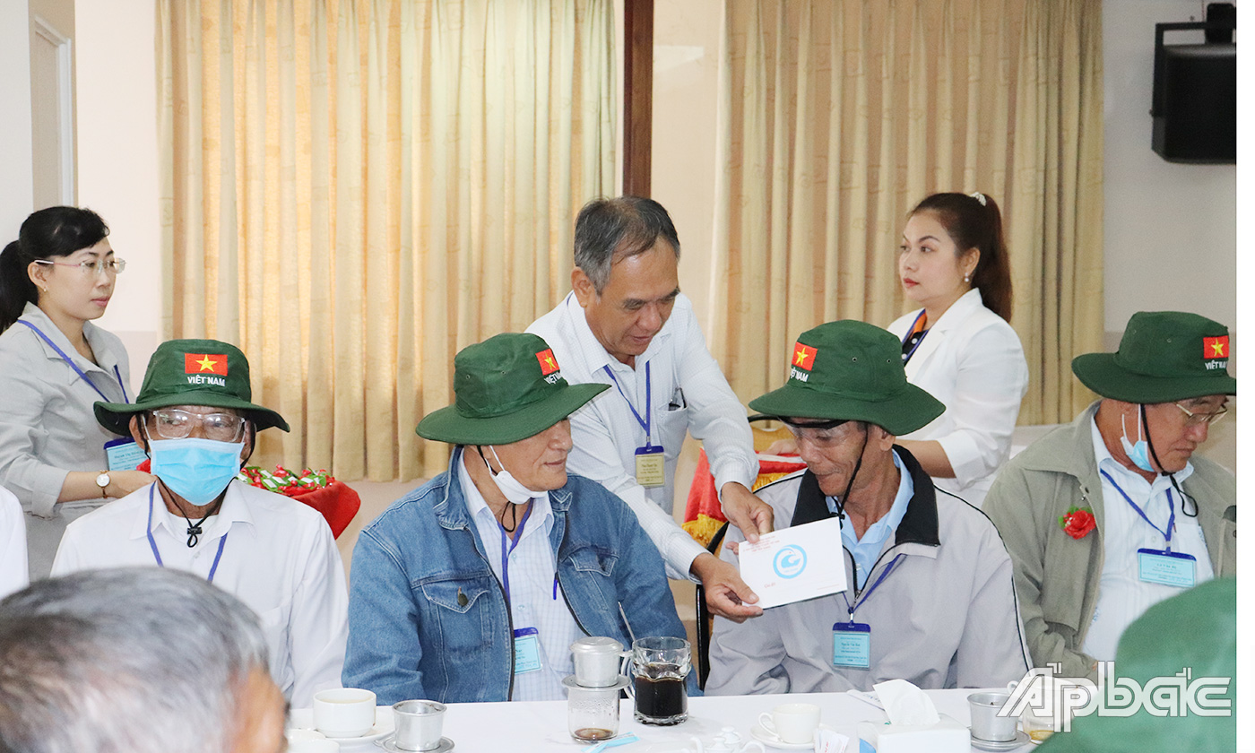Phó Giám đốc Sở Lao động Thương binh và Xã hội tỉnh Phan Thanh Vân cài hoa và tặng quà cho người có công trước khi tham quan thủ đô Hà Nội.