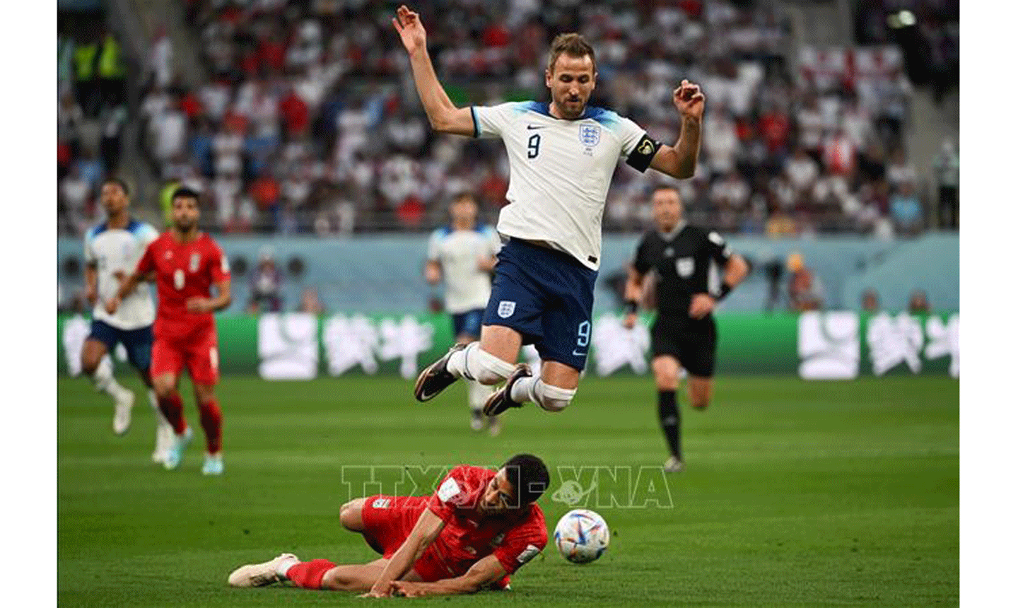 Pha vào bóng quyết liệt của hậu vệ Iran để ngăn cản đường lên bóng của Harry Kane, đội tuyển Anh. Ảnh: THX/TTXVN