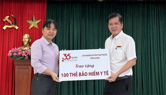 Ông Nguyễn Thành Thắng, Phó Giám đốc Agribank huyện Tân Phước trao biển tượng trưng 100 thẻ bảo hiểm y tế cho Bà Đặng Thị Ngọc Hiền, Phó Giám đốc Bảo hiểm Xã hội huyện Tân Phước