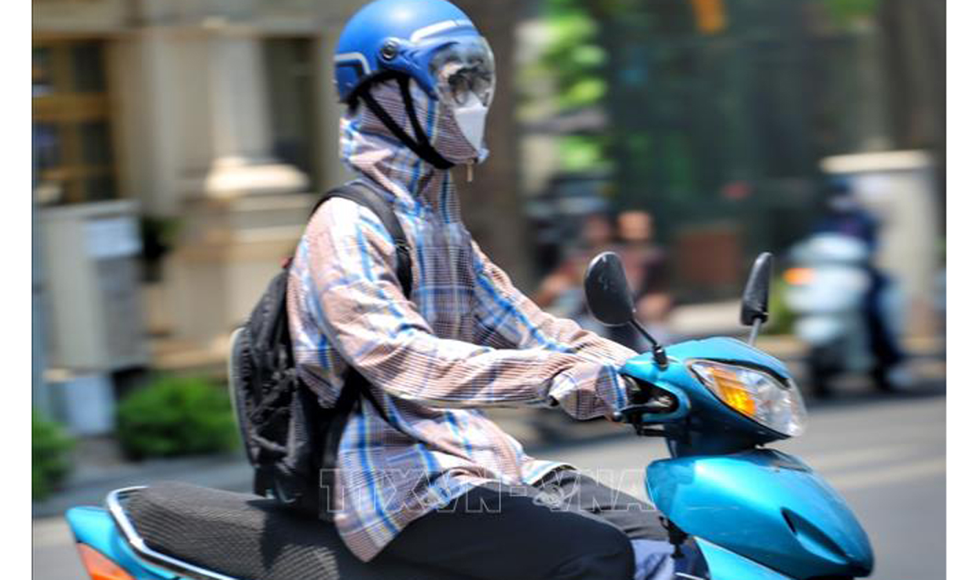 Người ra đường lúc nắng nóng cần mặc quần áo chống nắng, đeo kính râm để tránh sốc nhiệt. Ảnh: Tuấn Đức/TTXVN