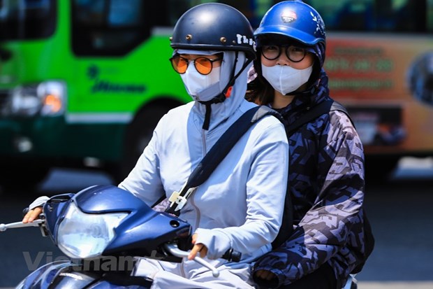 Người dân mặc áo chống nắng khi tham gia giao thông trong những ngày nắng nóng gay gắt. (Ảnh: Hoài Nam/Vietnam+)
