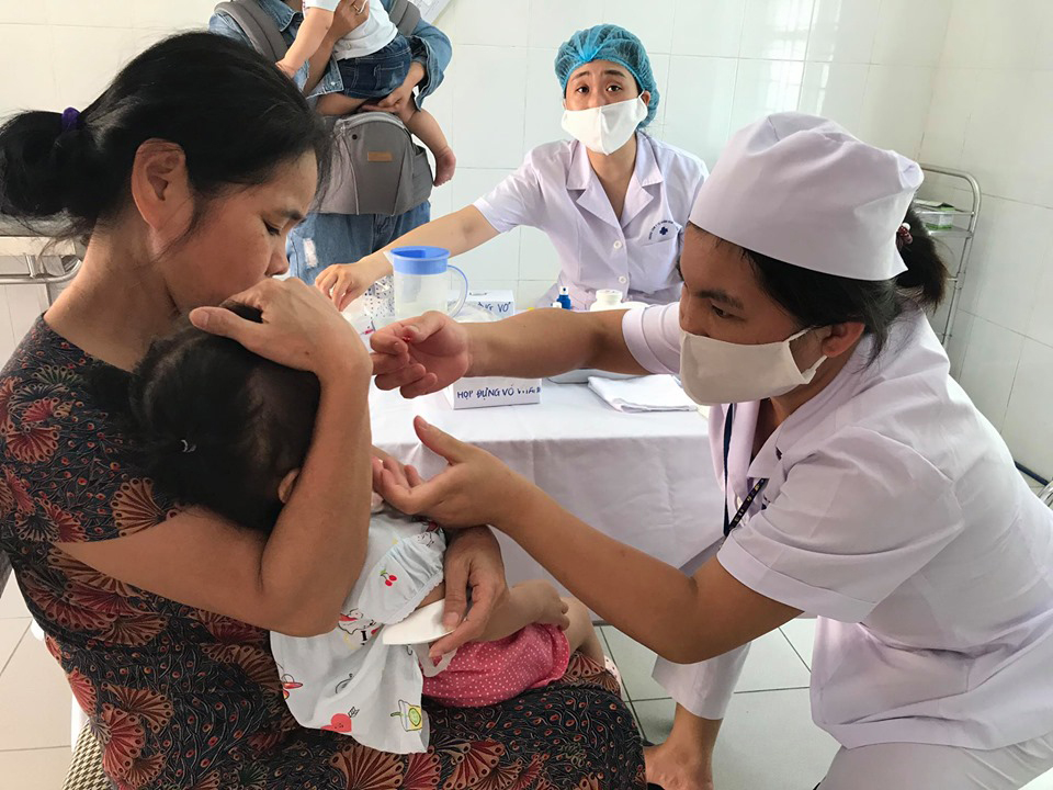 Người dân đưa trẻ đi uống Vitamin A tại trạm y tế. Ảnh: TTXVN