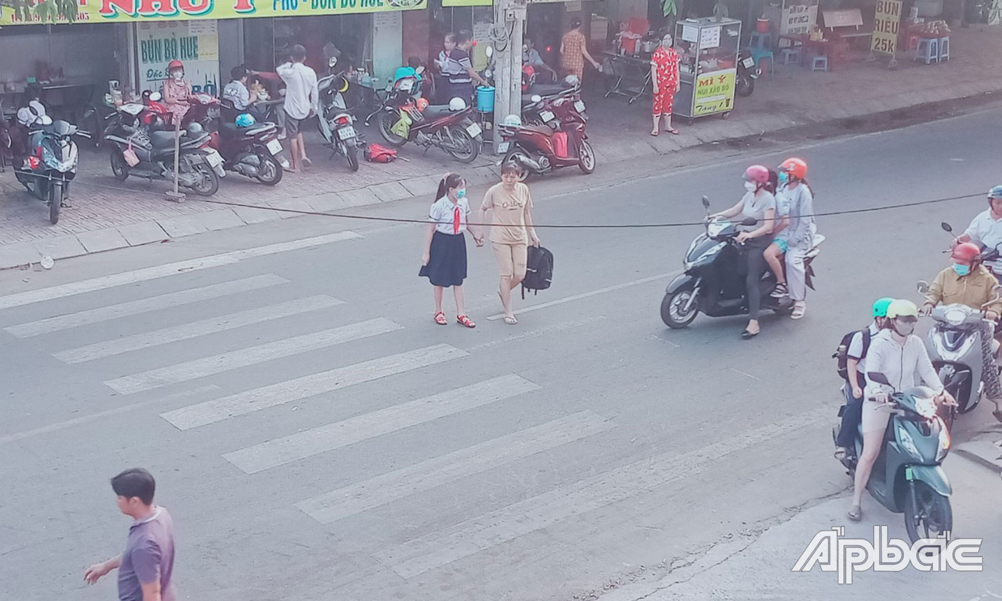 Phụ huynh dẫn con qua đường không đúng vạch kẻ đường trước Trường Tiểu học Thạnh Trị (TP. Mỹ Tho).
