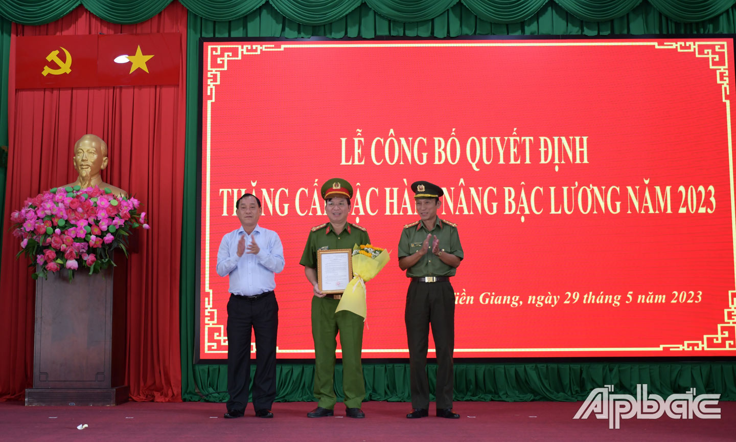 Đại tá Nguyễn Văn Nhựt trao Quyết định và đồng chí Nguyễn Văn Vĩnh tặng hoa chúc mừng Đại tá Nguyễn Văn Lộc, Phó Giám đốc Công an tỉnh đến niên hạn nâng bậc lương.  