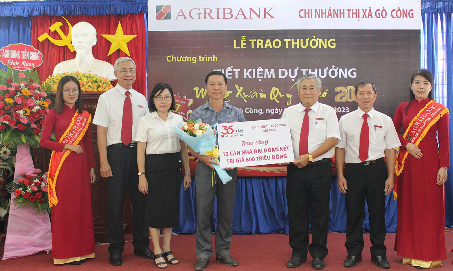 Ông Trần Phi Châu, Giám đốc Agribank TX. Gò Công trao biển tượng trưng số tiền 600 triệu đồng xây tặng 12 căn nhà đại đoàn kết cho ông Phạm Thanh Nguyên, Ủy viên Ban Thường vụ, Trưởng Ban Dân vận, Chủ tịch UBMTTQ TX. Gò Công –trước sự chứng kiến của bà Đinh Thị Thanh Tuyền, Phó Giám đốc Agribank Tiền Giang (thứ hai từ trái) và Ban Giám đốc Agribank TX. Gò Công