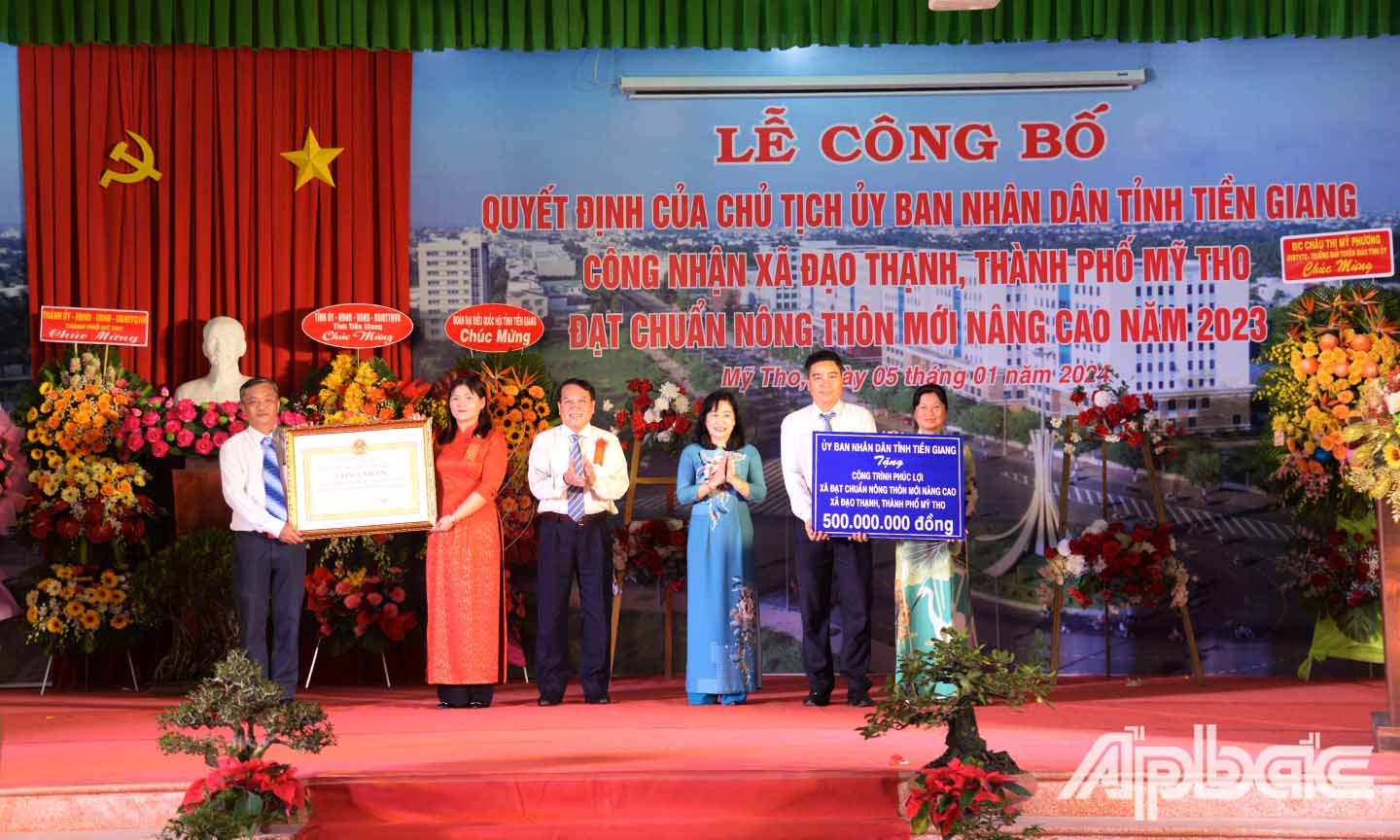 Đồng chí Châu Thị Mỹ Phương (thứ ba từ phải sang) và đồng chí Phạm Văn Trọng (thứ ba từ trái sang) trao bằng công nhận xã NTM nâng cao và bảng tượng trưng công trình phúc lợi cho xã Long An.