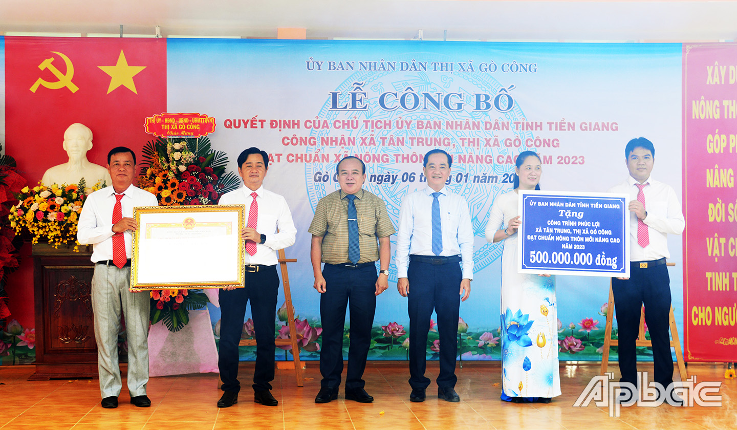 Đồng chí Nguyễn Chí Trung (thứ 3 từ trái sang) và đồng chí Nguyễn Kiên Cường (thứ 3 từ phải sang) trao bằng công nhận xã đạt chuẩn NTM nâng cao và bảng tượng trưng công trình phúc lợi cho UBND xã Tân Trung.