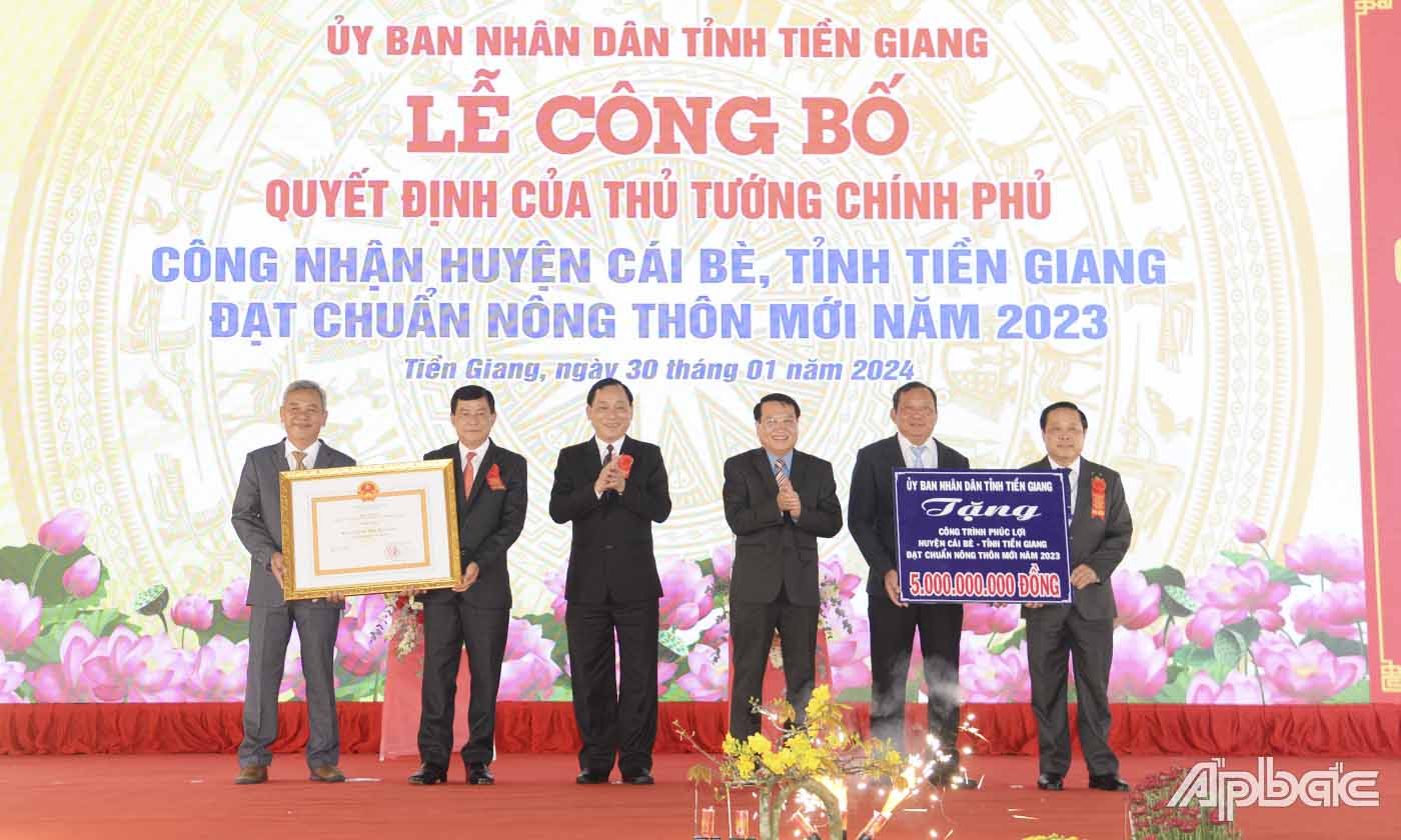 Đồng chí Nguyễn Văn Vĩnh, Phó Bí thư Tỉnh ủy, Chủ tịch UBND tỉnh (thứ 3 từ trái sang) và đồng chí Phạm Văn Trọng, Phó Chủ tịch UBND tỉnh (thứ ba từ phải qua) traong bằng công nhận của Thủ tướng Chính phủ và bảng tượng trung tặng công trình phúc lợi trị giá 5 tỷ đồng cho huyện Cái Bè.