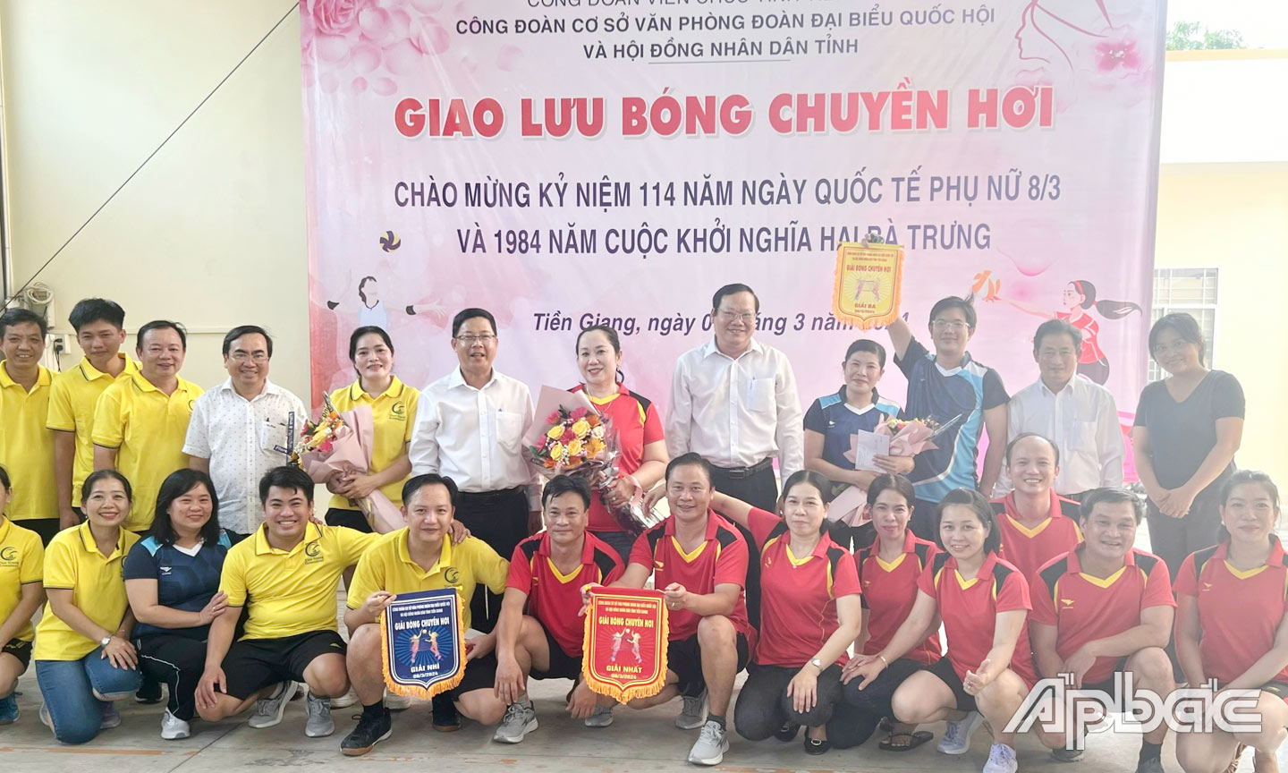 Ông Trần Thanh Nguyên (thứ 5 từ trái qua) và ông Nguyễn Hữu Lợi (thứ 7 từ trái qua) trao cờ và hoa cho các đội tham gia giao lưu bóng chuyền hơi .