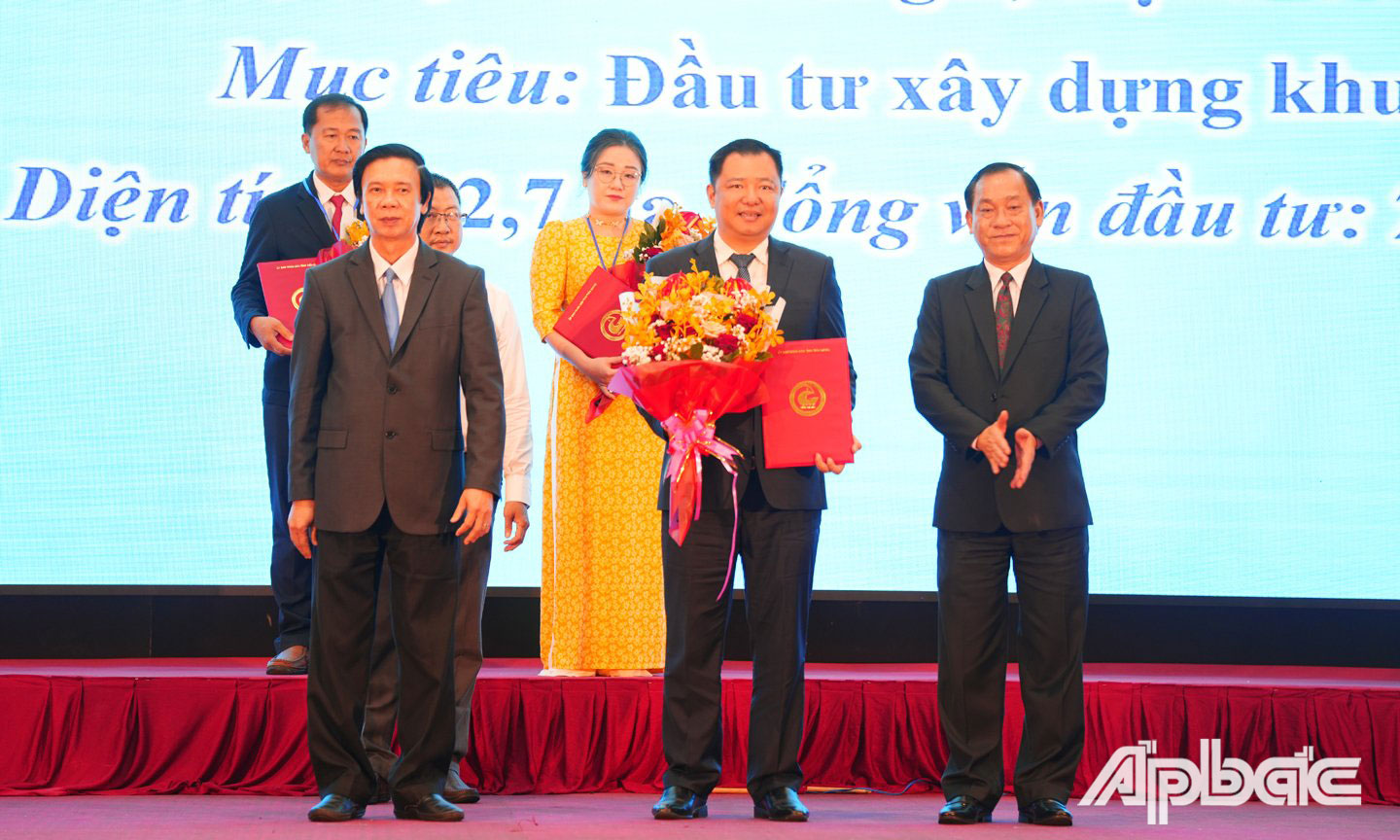 Đồng chí Nguyễn Văn Danh và đồng chí Nguyễn Văn Vĩnh trao Quyết định Chấp thuận chủ trương đầu tư, Giấy chứng nhận đăng ký đầu tư và tặng hoa chúc mừng nhà đầu tư.