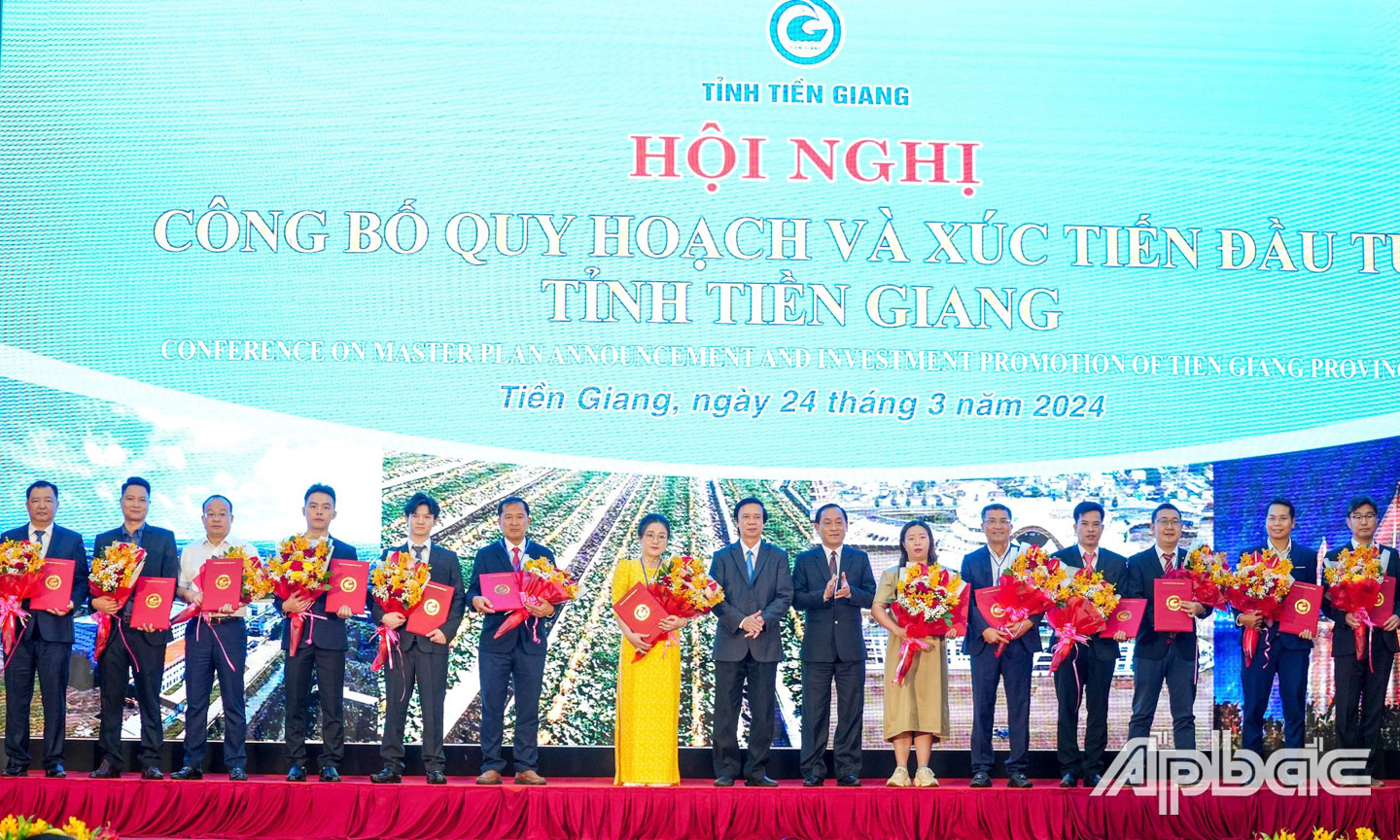 Đồng chí Nguyễn Văn Danh, Bí thư Tỉnh ủy Tiền Giang và đồng chí Nguyễn Văn Vĩnh, Chủ tịch UBND tỉnh Tiền Giang trao Quyết định Chấp thuận chủ trương đầu tư, Giấy chứng nhận đăng ký đầu tư và tặng hoa chúc mừng các nhà đầu tư.    Ảnh: VĂN THẢO