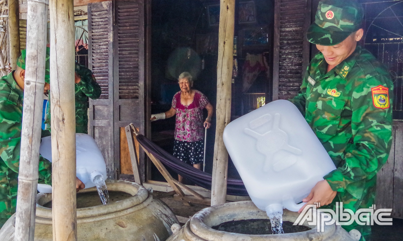 Cán bộ, chiến sĩ Đồn Biên phòng Tân Thành vận chuyển nước cho hộ người già neo đơn, khó khăn. 