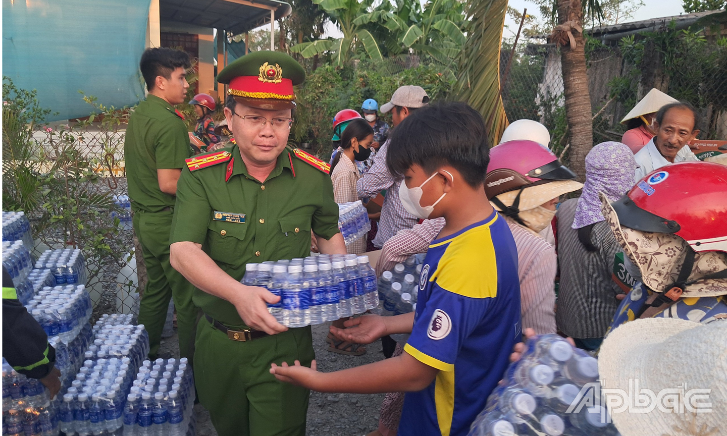 Đại tá Nguyễn Minh Tân, Phó giám đốc Công an tỉnh Tiền Giang tham gia chương trình và trực tiếp phát nước cho người dân tại xã Kiểng Phước, huyện Gò Công Đông. Ảnh: Lê Hoài