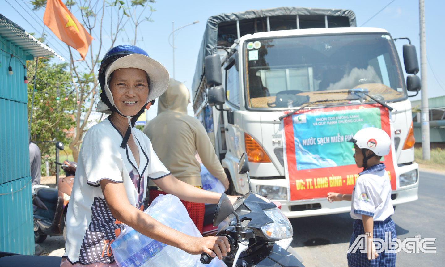 Bà Ngô Thị Lệ Hằng tươi cười khi được các nhà hảo tâm hỗ trợ nước suối.