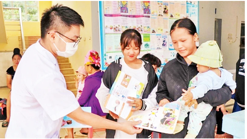 Cán bộ Trạm Y tế xã Mường Cai, huyện Sông Mã, tỉnh Sơn La phát tờ rơi tuyên truyền về công tác dân số cho nhân dân. (Ảnh HUYỀN TRANG)