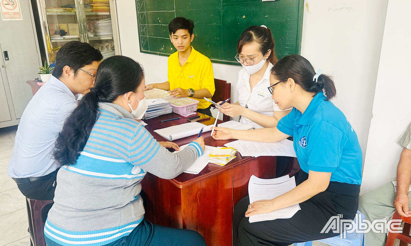 Viên chức BHXH tỉnh vận động người hưởng lương hưu nhận tiền qua  tài khoản cá nhân ATM tại điểm chi trả phường 5, TP. Mỹ Tho.