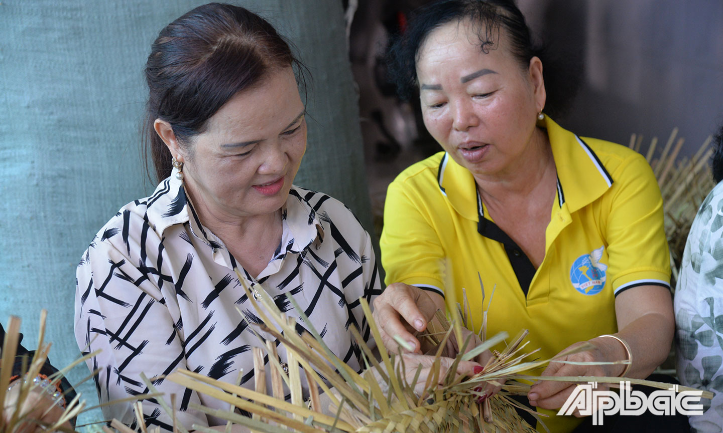 Chị Nguyễn Thị Bé Hai (bên phải) tận tình hướng dẫn chị em phụ nữ đan bàng.