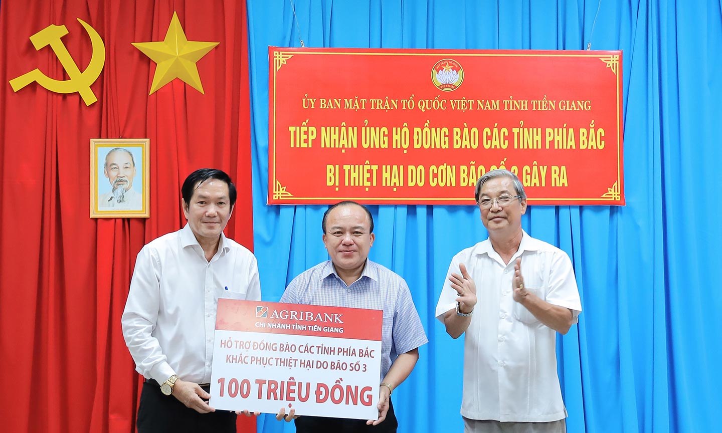 Giám đốc Agribank chi nhánh tỉnh Tiền Giang Trương Văn Đoàn (bìa trái) trao biển tượng trưng số tiền hỗ trợ 100 triệu đồng cho đồng chí Nguyễn Chí Trung, Ủy viên Ban Thường vụ Tỉnh ủy, Chủ tịch Ủy ban MTTQ Tỉnh Tiền Giang.