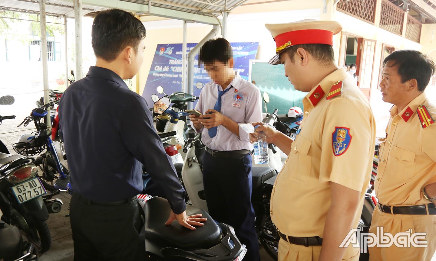 Kiểm tra giấy phép lái xe của 1 học sinh đủ điều kiện điều khiển xe máy trên 50Cc tại bãi xe trường THPT Nguyễn Đình Chiểu.