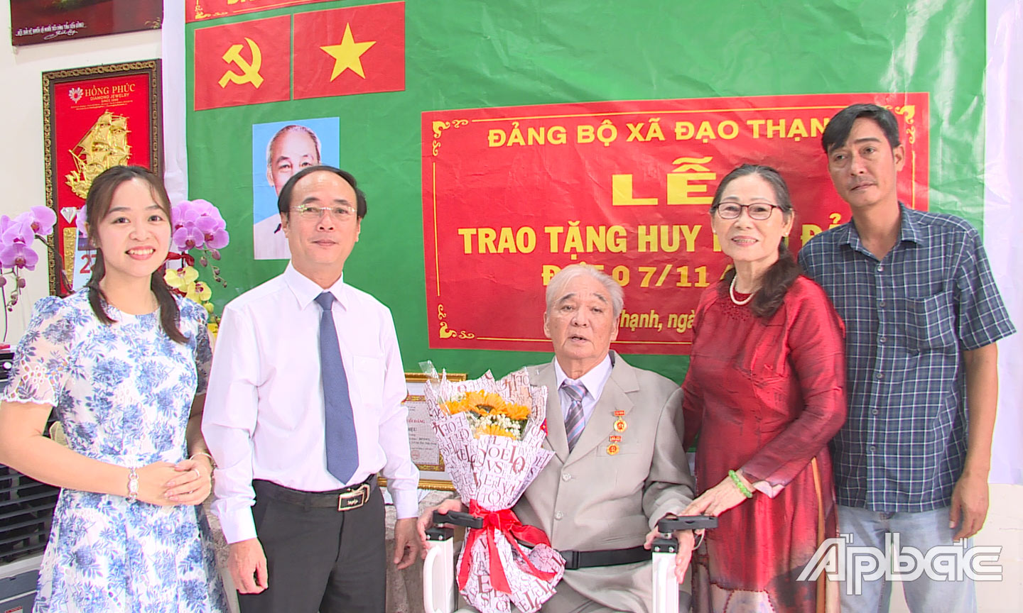 Đồng chí Trần Kim Trát, cùng gia đình tặng hoa chúc mừng đảng viên Trần Hoàng Diệu nhận Huy hiệu 55 năm tuổi Đảng.