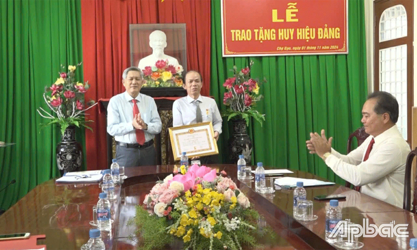 đồng chí Nguyễn Hồng Hữu, Tỉnh ủy viên, Bí thư Huyện ủy Chợ Gạo trao Huy hiệu 30 năm tuổi Đảng cho đồng chí Cao Văn Ngữ