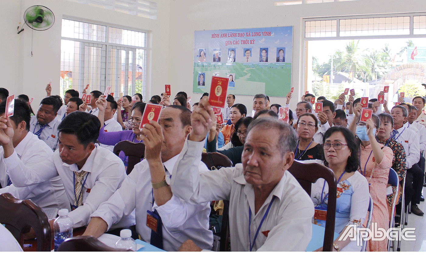 Các đại biểu giơ thẻ đảng viên để biểu quyết.
