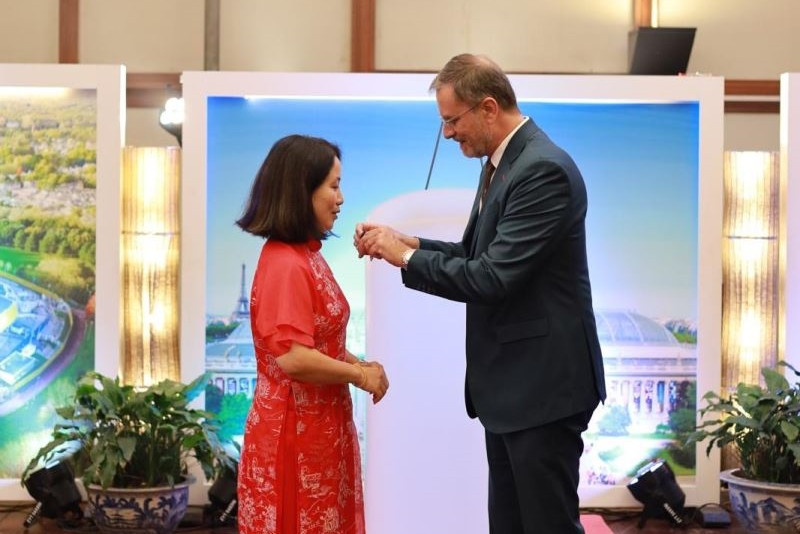 Đại sứ Cộng hòa Pháp Olivier Brochet thay mặt Chính phủ trao tặng huân chương Cành cọ hàn lâm cho TS.KTS Nguyễn Thái Huyền. Ảnh: HAU