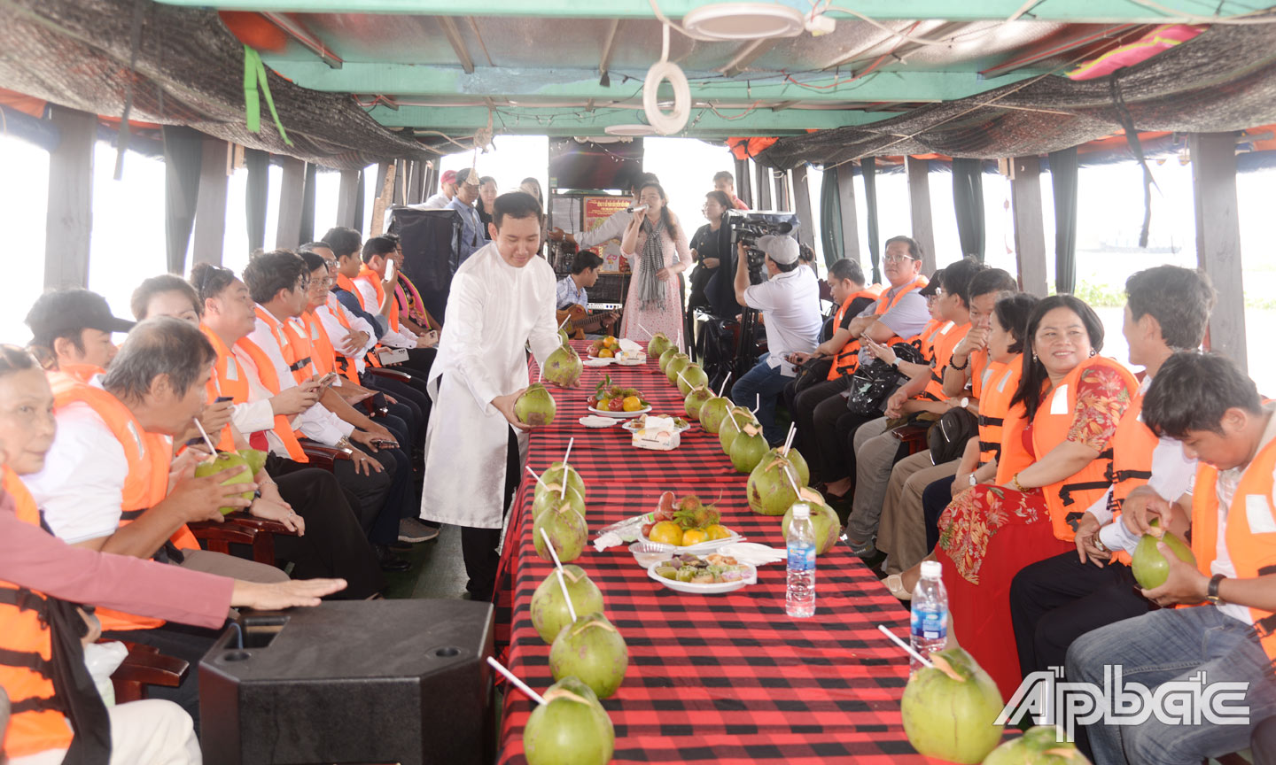 Đoàn khảo sát thưởng thức nước dừa khi di chuyển bằng du thuyền trên sông Tiền. Ảnh: C. THẮNG