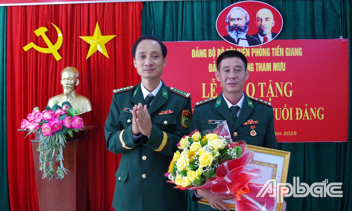 Đại tá Trần Chí Cường trao quyết định và tặng hoa chúc mừng Thượng tá Lại Văn Lục. 