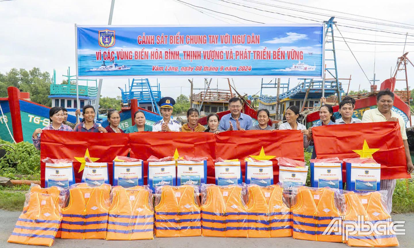 Trao quà và cờ Tổ quốc cho đại diện chủ phương tiện đánh bắt, thu mua hải sản tại khu neo đậu tàu thuyền thị trấn Vàm Láng (nay là xã Gia Thuận).